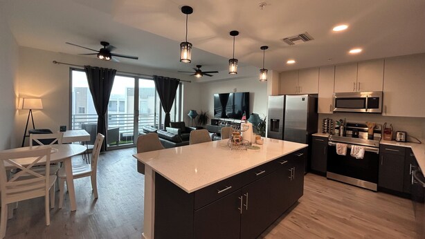 A modern kitchen with a central island, built-in appliances, and a dining area with a view to the outside.