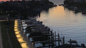 A marina at sunset with boats docked along a waterfront promenade.