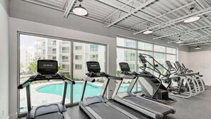 A gym with treadmills and a pool view.