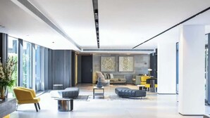 Un vestíbulo espacioso y moderno con una zona de estar central, ventanas amplias y un diseño minimalista.