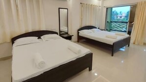 A hotel room with two beds, a large mirror, an air conditioning unit, and a balcony with a view. - Beach Aura (Nagaon)