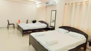A hotel room with two beds, a chair, a desk, and a mirror. - Beach Aura (Nagaon)