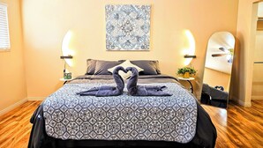 Een hotelkamer met een bed, een spiegel aan de muur, een plafondventilator en een decoratief wandobject.