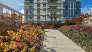 A modern multi-story residential building with balconies and a landscaped garden area.