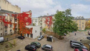 Un estacionamiento con varios autos, un pequeño edificio con un cartel y un árbol de follaje rojo.