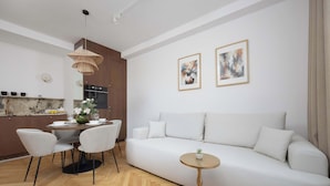 Una sala moderna con sofá, mesa de comedor, sillas y una pequeña mesa redonda con una planta.