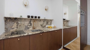 Una cocina moderna con encimera de mármol, armarios de madera y pileta integrada.