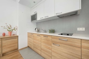 A modern kitchen with white cabinets, a stainless steel sink, and a microwave.