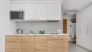 A modern kitchen with white cabinets, a built-in microwave, a kettle, and a sink. - Stylish Studio in the Center | Air Conditioning | Parking (Wrocław)
