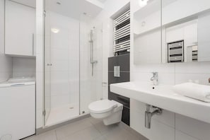 A modern bathroom with a glass-enclosed shower, a white toilet, a sink with a mirror, and a towel rack.