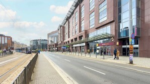 A street with a tram track, buildings, and pedestrians. - Stylish Studio in the Center | Air Conditioning | Parking (Wrocław)