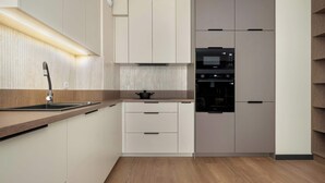 A modern kitchen with a built-in oven, microwave, and a stainless steel sink.