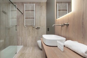 A modern bathroom with a glass shower enclosure, a white sink, and a wooden vanity.