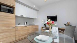 A modern kitchen with wooden cabinets, a built-in microwave, and a flat-screen TV.