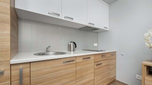 A modern kitchen with a stainless steel sink, wooden cabinets, and a white countertop.