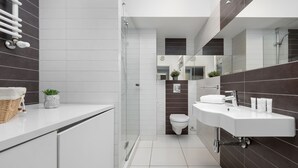 A modern bathroom with a shower, toilet, and sink.