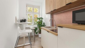 A modern kitchen with white cabinets, a wooden countertop, a sink, and a large window.