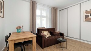 A modern living room with a wooden dining table, a brown sofa, and a small black side table.