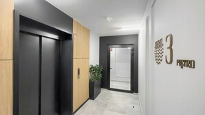 A hallway with a modern elevator, a potted plant, and a door labeled "3 Pietro".
