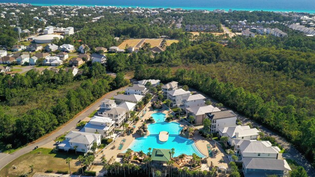 An aerial view of a residential area with a large swimming pool surrounded by houses and greenery. - 30a Tropical Breeze Beach Home Near Beach! 6Seater Lsv, Pool, Gated Community (Santa Rosa Beach)
