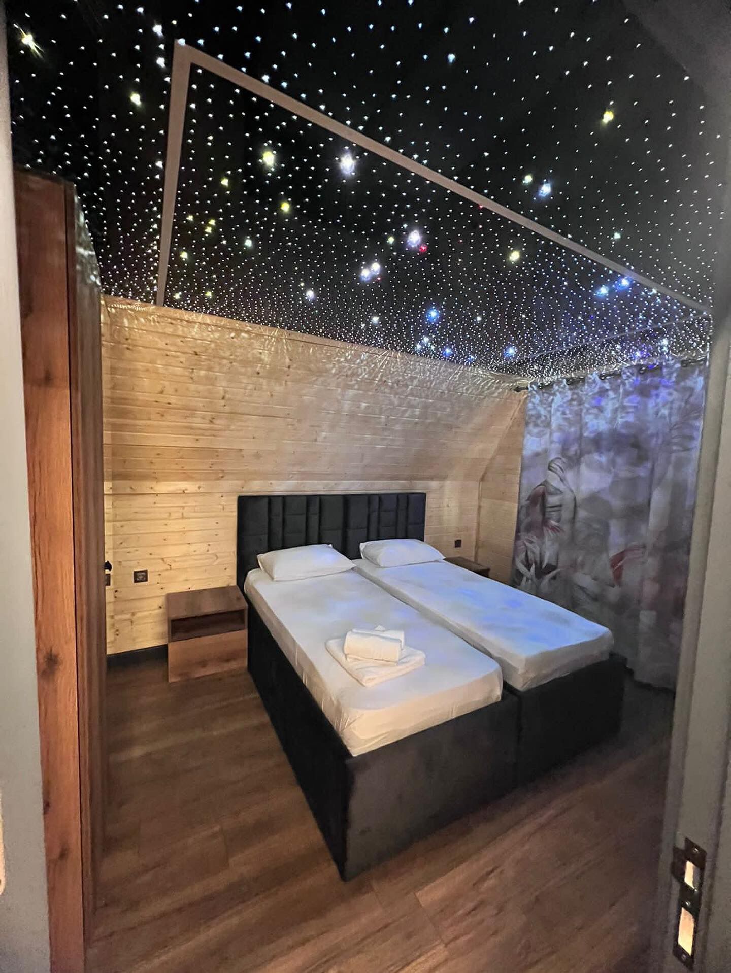 Ein Schlafzimmer mit schrägem Dach, Holzwänden und einem Bett mit weißen Leinen.