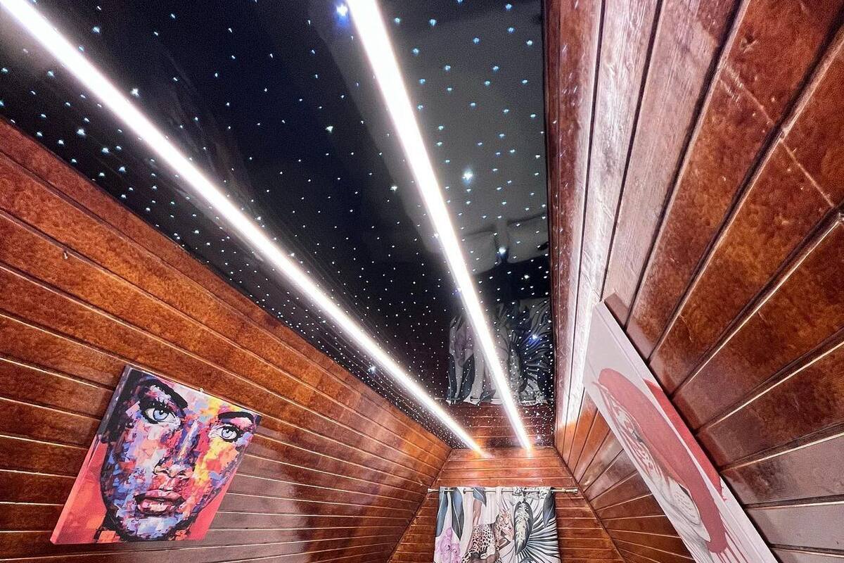 Ein modernes Schlafzimmer mit schrägen Wänden, Holzpaneelen und einem Bett mit weißer Bettwäsche, inklusive Wandbildern.