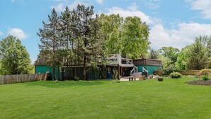 Una casa con un patio trasero amplio, un área de estar techada al aire libre y una terraza de madera.