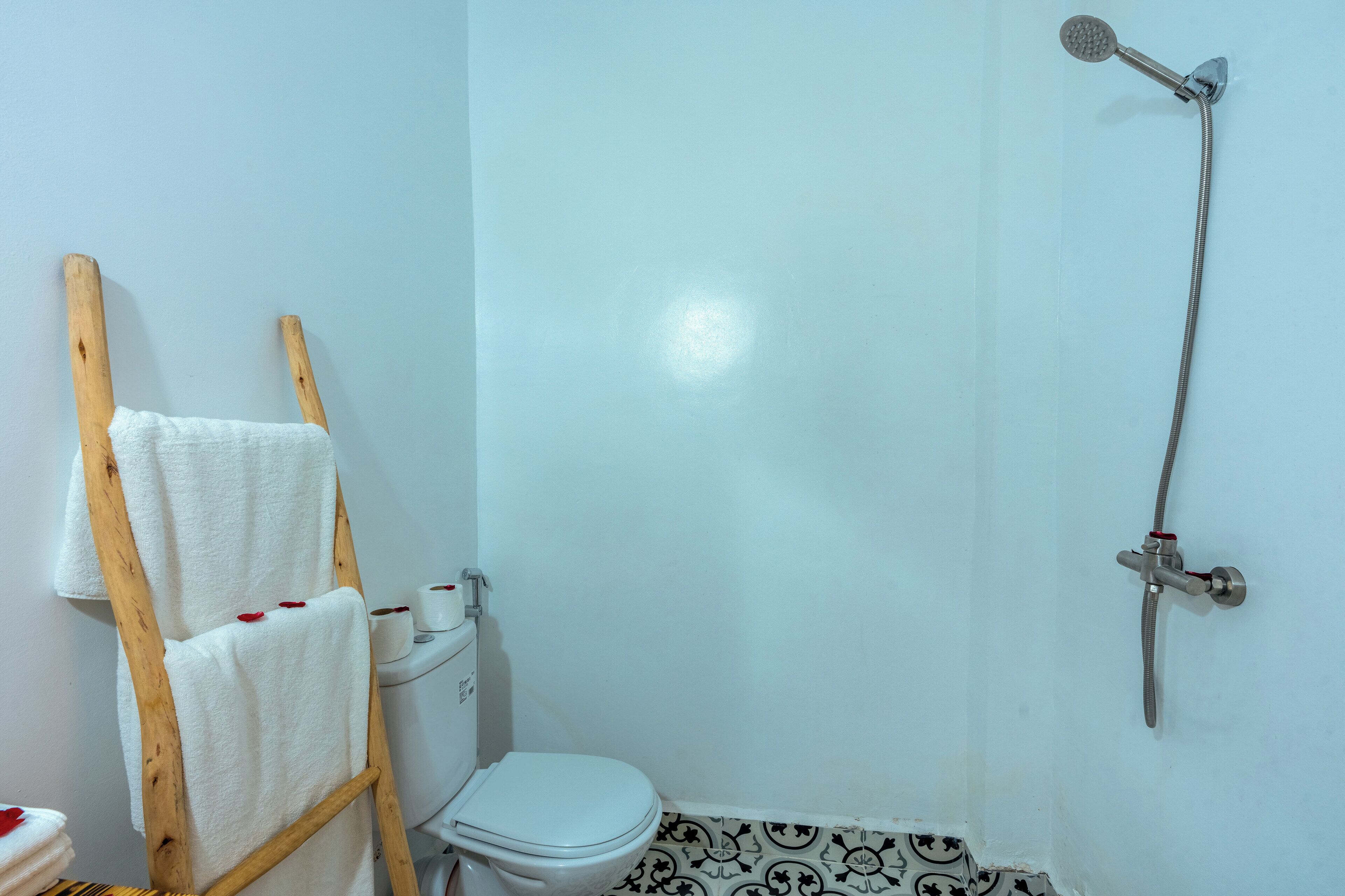 Un baño con inodoro, ducha y una escalera de madera con toallas.