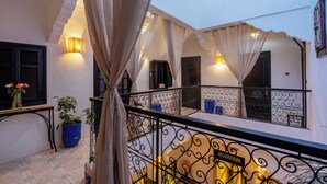 Un balcon avec des balustrades en fer forgé, un pot de fleurs et un luminaire fixé au mur.