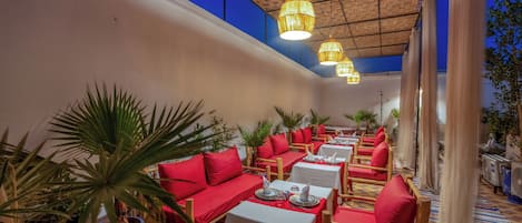 A restaurant with red cushioned seating, white tables, and hanging lights.