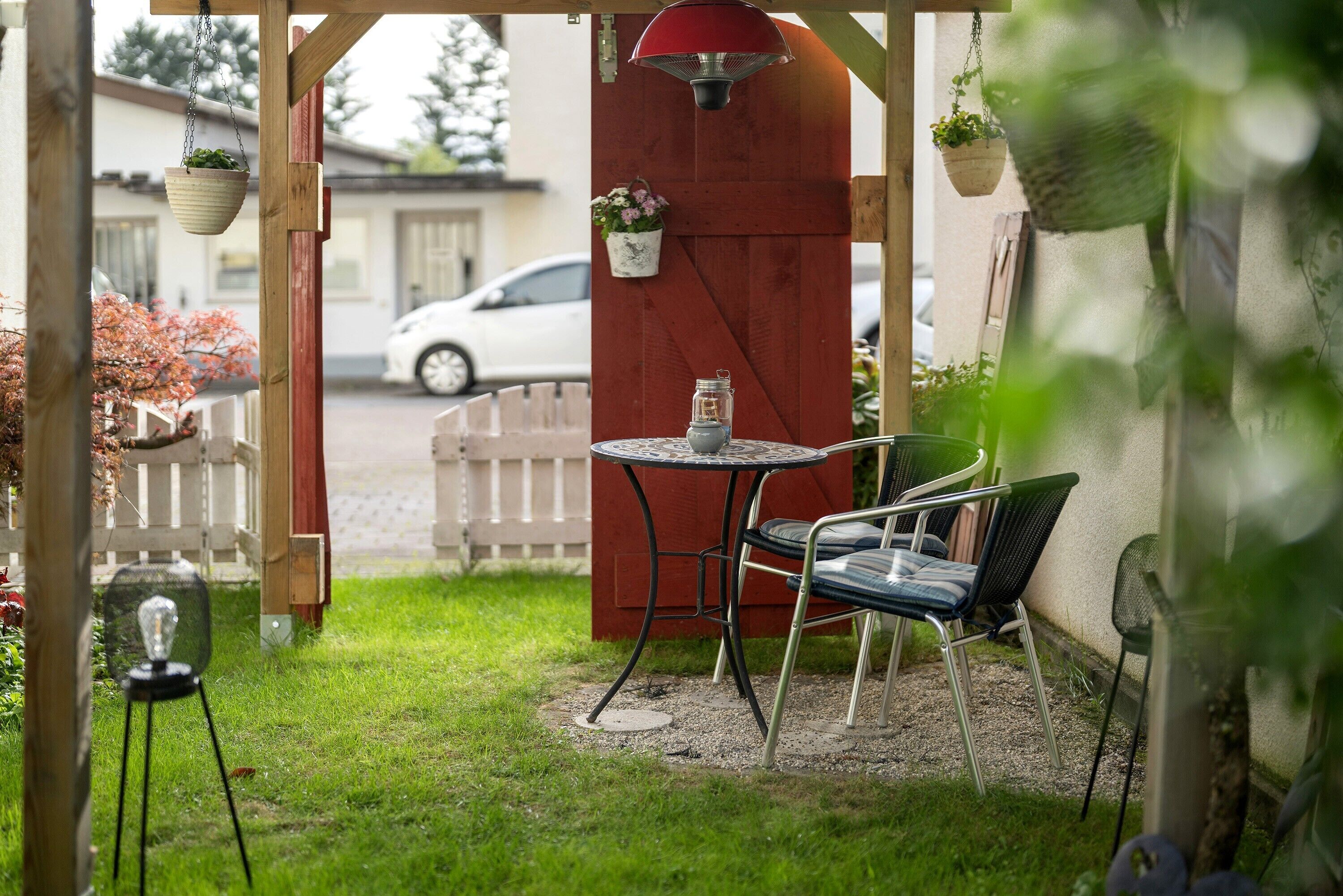 Une terrasse avec une table et des chaises, un luminaire suspendu et des plantes en pot.