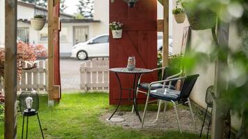 Une terrasse avec une table et des chaises, un luminaire suspendu et des plantes en pot.