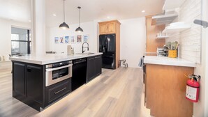 Een moderne keuken met zwarte apparaten, houten keukenkastjes en een wit aanrecht.