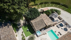 An aerial view of a property with a swimming pool, outdoor seating, and a fenced garden area.