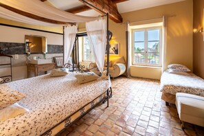 A bedroom with a bed, two bedside tables, a nightstand, a window with curtains, a mirror, and a view of the outside.