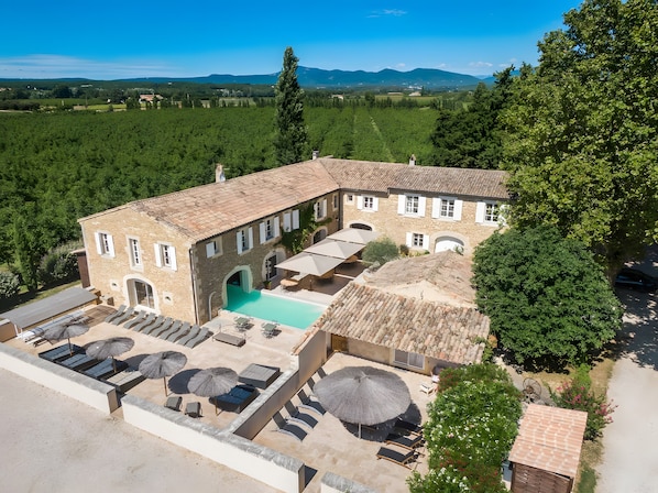 A stone building with a swimming pool, outdoor seating, and a view of the surrounding landscape.