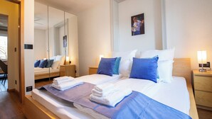 A modern hotel room with a large bed, a mirror, a painting, and a nightstand with a lamp. - Special *Roger F. Rabbit 2* Apartment (Basel)