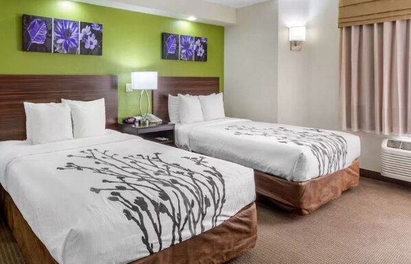 Une chambre d’hôtel avec deux lits, une table de chevet, une lampe et des œuvres d’art accrochées aux murs.