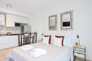 Una habitación de hotel con cama, escritorio, microondas y una pequeña cocina.