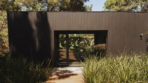 A modern building with a wooden pathway leading to an open doorway.