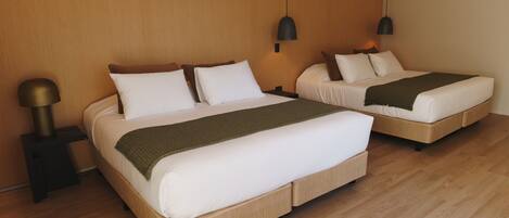 Habitación de hotel con dos camas, suelo de madera e iluminación colgante moderna.