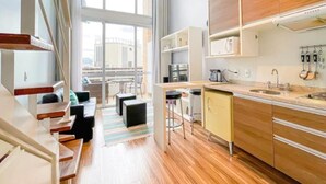 A modern kitchen with wooden cabinets, a dining area with a table and chairs, and a large window providing a view of the city. - Maximus Luxury in Nyc Berrini (São Paulo)