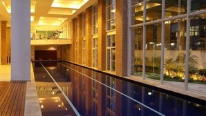 A modern hotel corridor with a glass railing, large windows, and a view of a landscaped garden. - Maximus Luxury in Nyc Berrini (São Paulo)