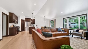 Una cocina moderna con armarios de madera oscura, un refrigerador de acero inoxidable y un comedor con un ventanal grande.