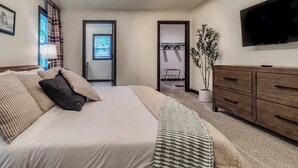 Un dormitorio con una cama, un televisor, un aparador y una planta.