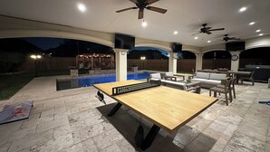Area patio esterna con piscina, posti a sedere e ventilatori a soffitto.