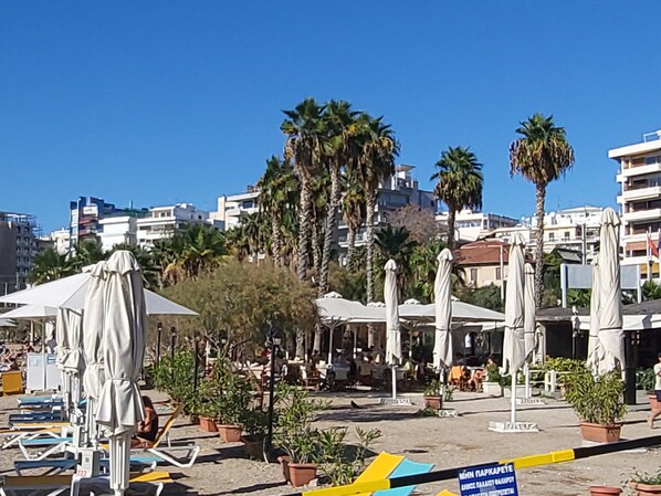 A beachfront area with sun loungers, umbrellas, and potted plants.