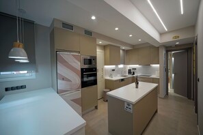 A modern kitchen with built-in appliances, a central island, and a pendant light.