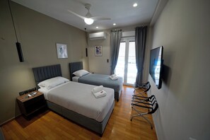 A hotel room with two beds, a TV, a ceiling fan, and a window with curtains.