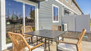 A patio with a table and chairs, a sliding glass door, and an air conditioning unit. - NEW Ivy Streat Retreat in Ephrata, Sleeps 10, EV Charger + Foosball + Air Hockey (Ephrata)